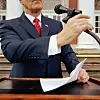 A speaker at a podium holding papers and a microphone.