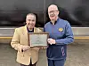 Two men holding an award plaque together.