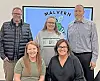 Five individuals posing in front of a Malvern logo.
