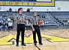 Two referees with a basketball on the court.