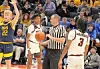 Referee with basketball and players on court.