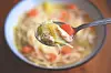 Spoon with chicken noodle soup close-up.