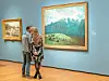 Couple viewing a landscape painting in an art gallery.