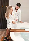 Couple in robes by a spa tub.