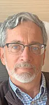 Close-up of a man with gray hair and glasses.