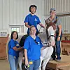 Participants and volunteers with a horse in a riding facility.