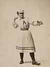 Female baseball player in vintage uniform throwing a ball.
