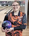 Young bowler holding a bowling ball in a bowling alley.
