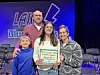 Family with a spelling bee certificate on stage.