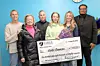 Group poses with a large scholarship check at a community event.