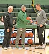 Coaches shaking hands on a basketball court.