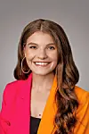 Smiling woman in a pink and orange blazer.