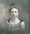 Vintage portrait of a young woman with curly hair and a ruffled blouse.