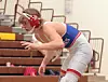 Wrestler in red and blue uniform poised on the mat.