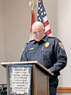 Police officer at podium speaking during an event.