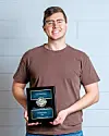 Young man holding an award plaque with a smile.