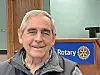 Smiling man in front of Rotary Club logo.
