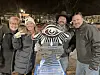 Four people smiling with an ice sculpture at night.