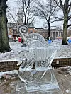 Ice sculpture of a swan and harp in a snowy park.