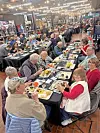 People seated at tables enjoying a meal in a communal setting.