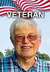 Smiling veteran with glasses in front of an American flag.