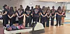 Bowling team in black shirts stands together at a bowling alley.