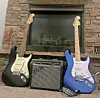 Two electric guitars and an amplifier near a fireplace.