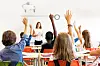 Students with raised hands in a classroom.