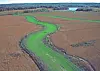Aerial view of a green river winding through brown fields.