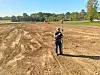 Surveyor measuring land in a cleared field.