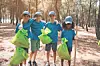 Children holding green bags in a forest during a cleanup activity.