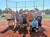 Group of people on a softball field under clear skies.