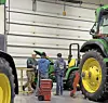 Technicians working on a tractor in a workshop.