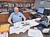 Man at a desk with papers and books in an office.