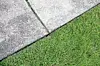 Concrete sidewalk and green grass meeting at an angle.