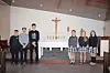 Students in uniforms stand in front of a church altar.
