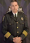 Police chief in uniform at an event backdrop.