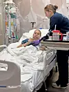 Patient in hospital bed with nurse attending to them.