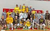 Wrestling team in uniforms poses for a group photo indoors.