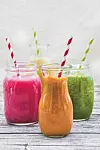 Four colorful smoothies in jars with straws.