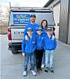 Family in blue clothing poses by a GSC Plumbing vehicle.