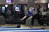 A bowler releasing a ball at a bowling alley.