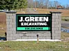 Sign for J. Green Excavating along a rural road.