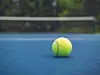 Close-up of a tennis ball on a blue court.