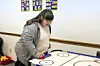 Girl playing air hockey in a classroom.