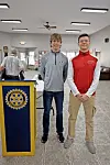 Two young men pose next to a Rotary Club podium.