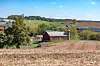 Rural landscape with a red barn and fields.