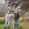 Three people holding a sign in a forested area.