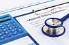 Medical billing statement, calculator, and stethoscope on a table.