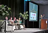 Panel discussion at a conference with speakers and audience.